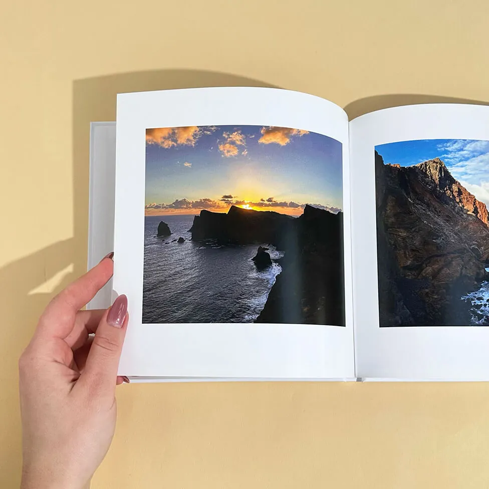 Open klikkie reisfotoboek met een zonsondergang aan de kust op de linkerpagina en kliffen aan zee op de rechterpagina
